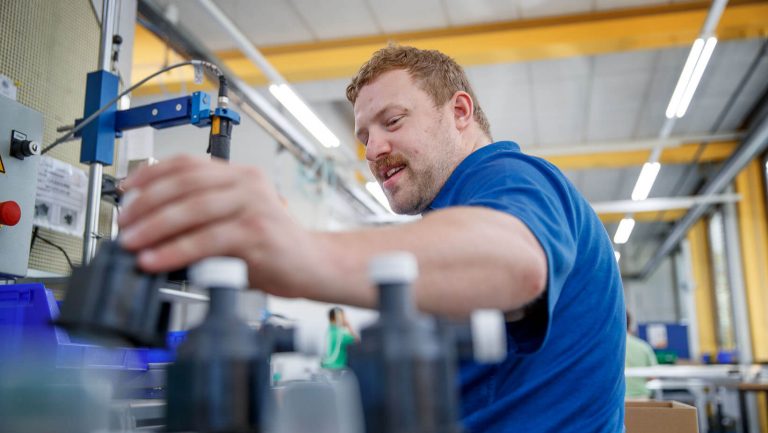 Ein Mann arbeitet erfreut an seinen Aufgaben in der Werkstatt