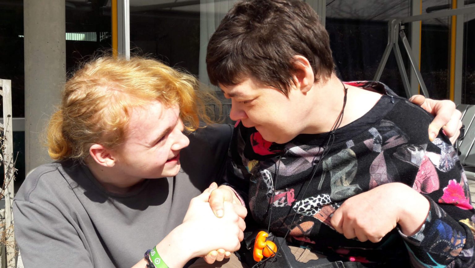 Ein FSJ-ler kommuniziert mit einer Frau im Rollstuhl.