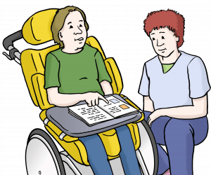 Eine Person sitzt im Rollstuhl und zeigt etwas in einem Heft auf einem Tischchen vor ihr. Eine andere Person kniet daneben.