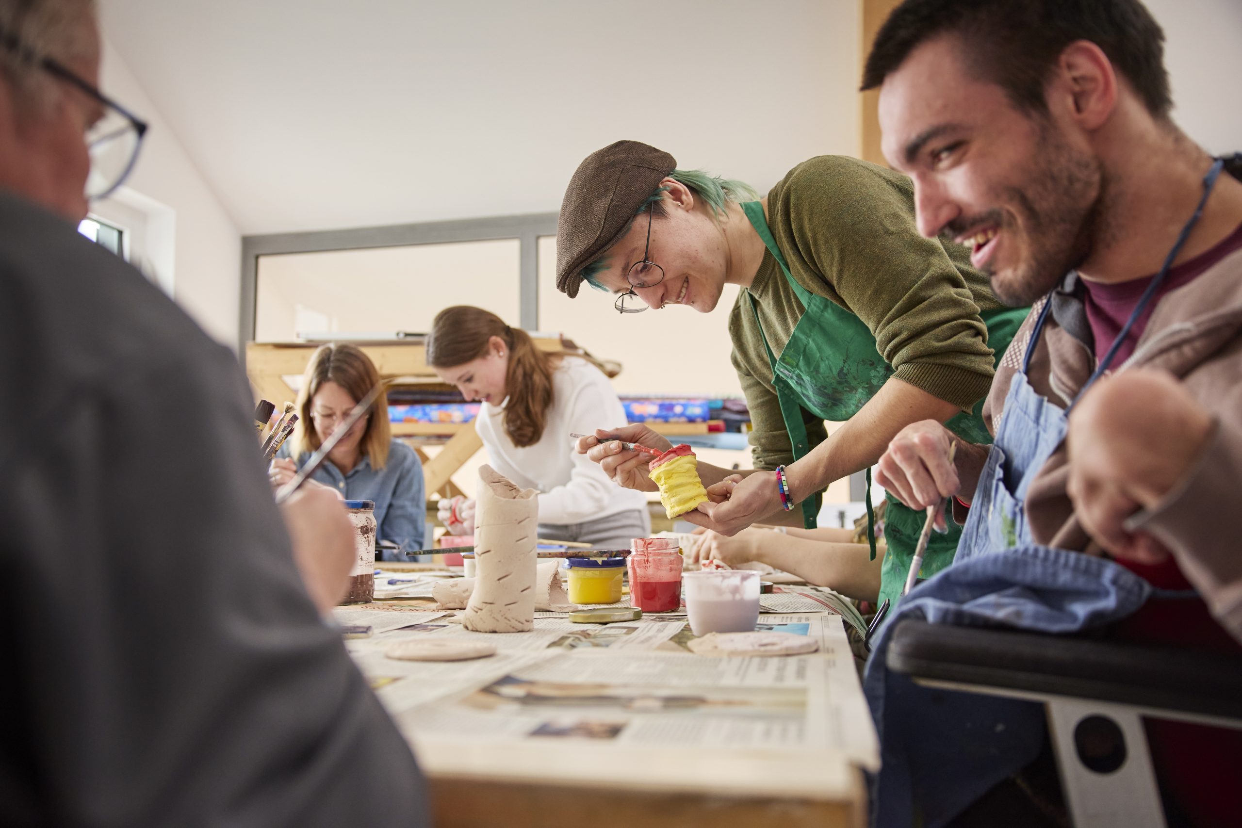 Menschen arbeiten mit Ton und Farben an einem Tisch