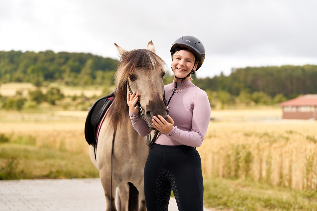 Eine Reiterin steht neben einem Pferd.