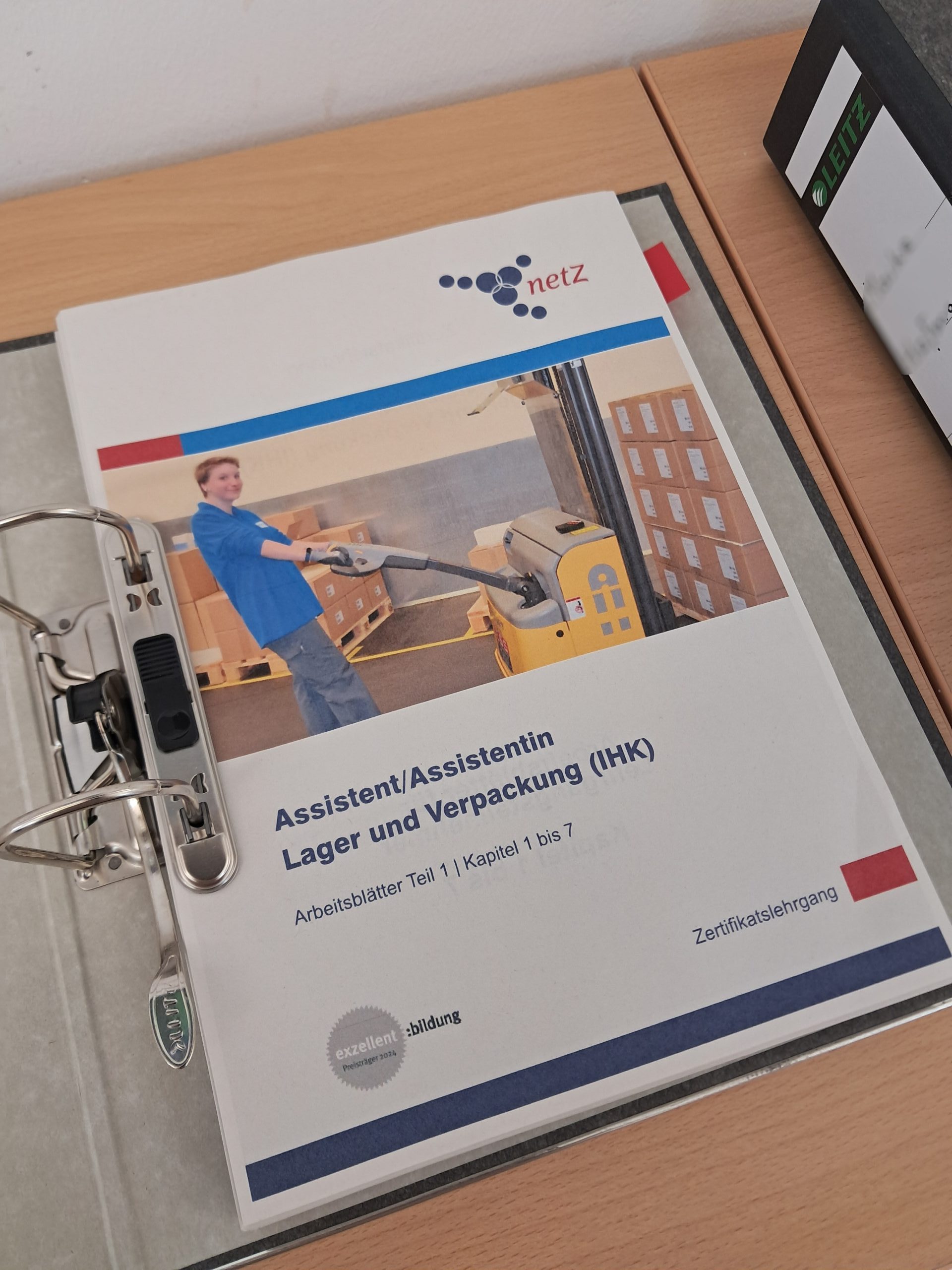 Ein Ordner mit Schulungsunterlagen. Auf dem Titelblatt steht: Assistent/ Assistentin Lager und Verpackung (IHK)