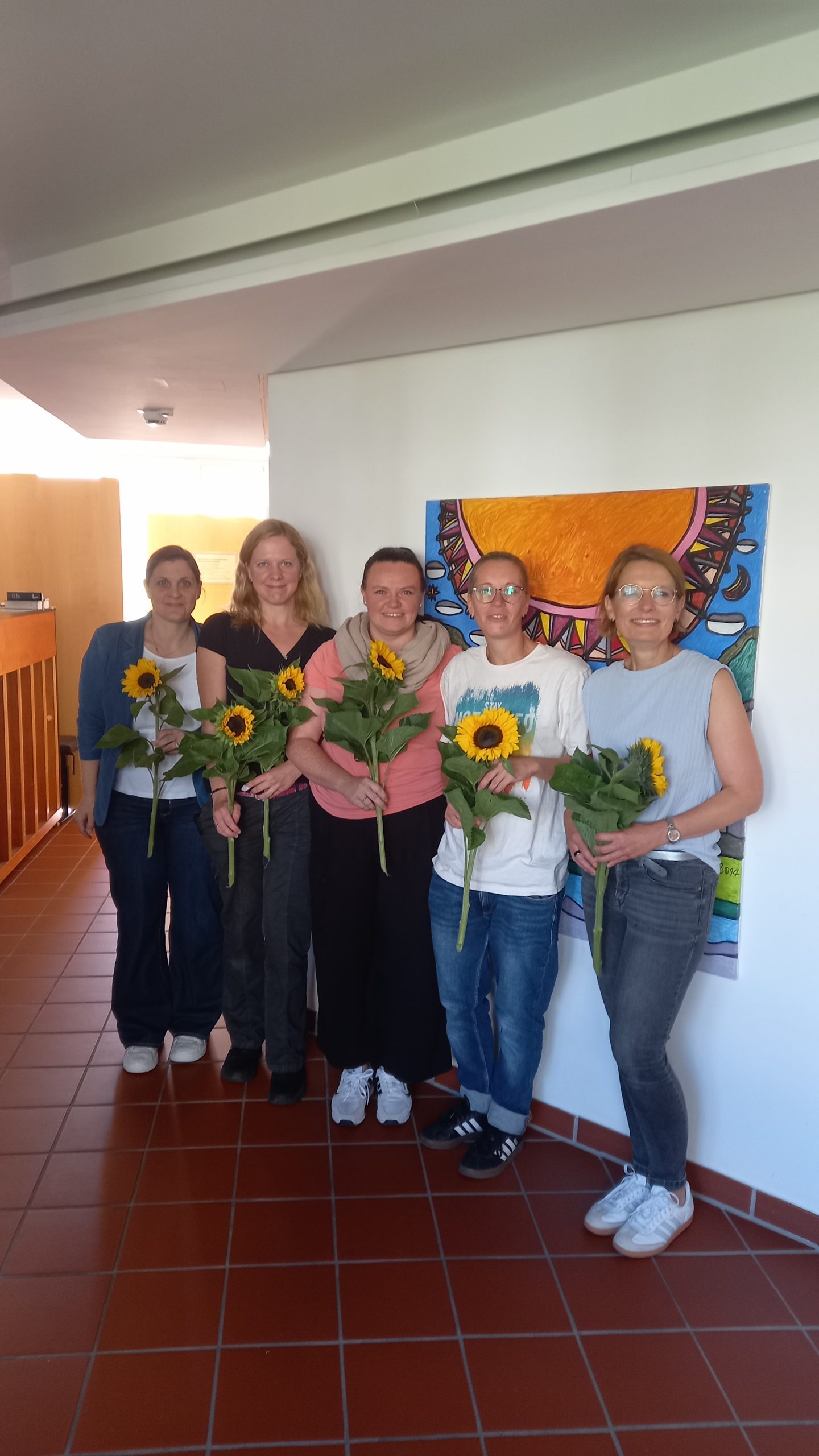 5 Mitarbeiterinnen der Seniorengruppe haben jeweils eine Sonnenblume in der Hand.