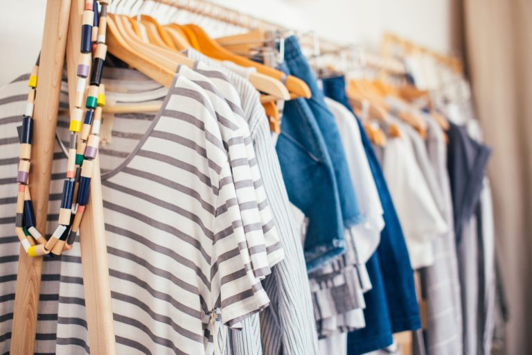 Zeitgenössische Bekleidungskollektion auf Holzkleiderbügeln mit gestreiften und Jeans-Stilen.
